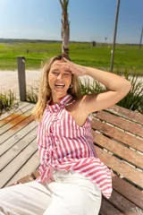 Camisa sin mangas con cuello halter y lazos decorativos en el frente. Diseño a rayas verticales rojas y blancas.