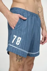 Short deportivo azul con finas rayas verticales blancas, cintura elástica y logo estampado en la pierna.