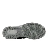 Championes urbanos New Balance modelo 1906R, color gris con detalles en amarillo y negro. Presentan una estructura técnica con paneles de malla y refuerzos sintéticos, logo N lateral y entresuela con tecnología de amortiguación.