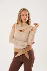 Polera beige de cuello alto con mangas largas y abertura en el pecho.