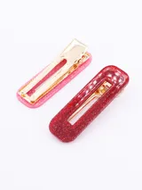 Set de dos broches para el pelo, uno rosa y otro rojo, con glitter y gancho metálico dorado.