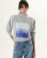 Buzo gris claro de algodón con cuello medio y estampa rectangular con diseño de paisaje marítimo en tonos azules.