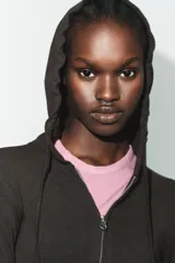 Sudadera cropped de punto con cierre frontal de cremallera metálica, capucha ajustable con cordones y mangas largas con puños en rib.