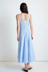 Vestido midi de color celeste con escote cuadrado y tirantes anchos. Presenta un diseño entallado en el torso con falda acampanada terminada en godets que aportan volumen y movimiento. Incluye cierre lateral con cremallera oculta.