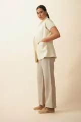 Chaleco color crema con solapas, corte entallado y bolsillos plaqué.