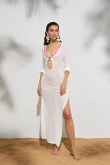 Vestido largo de tejido de punto blanco, con escote profundo en V, detalle de argolla frontal, mangas largas y tajo lateral en la falda.