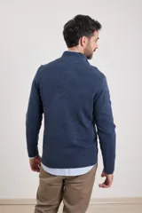 Sweater verde oliva de tejido acrílico con textura similar al cashmere, corte clásico, cuello alto con cierre metálico y tirador de cuerina ecológica.