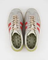 Zapatillas bajas Coolway Kizuna color gris claro con detalles en rojo y verde. Confeccionadas en gamuza y nylon, con ajuste de cordones, plantilla acolchada y suela de goma color miel.