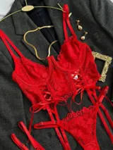 Conjunto de lencería rojo de encaje floral, compuesto por un corpiño tipo corset con aro y tirantes finos, una bombacha colaless regulable y ligas con cintas ajustables.