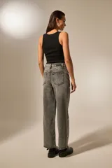 Pantalón de jean recto de tiro alto, color gris lavado con efecto acid wash. Presenta detalles de strass o apliques brillantes a lo largo de las costuras laterales exteriores.