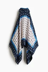 Top halter confeccionado en viscosa satinada de corte evasé, con cuello elevado, cintas para enlazar en la nuca, bajo redondeado y estampado geométrico en tonos azul marino, celeste y blanco.