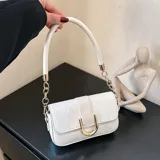 Cartera blanca con textura de cocodrilo, asa corta rígida y correa de cadena dorada.