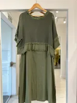 Vestido midi color verde militar, con superposición de tejido de red en la parte superior y detalles de flecos en los bordes de las mangas y el canesú.
