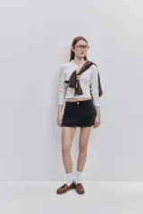 Top de calce al cuerpo color negro, confeccionado en tejido elástico con textura acanalada, con cuello camisero, mangas largas y recorte frontal tipo cut-out.