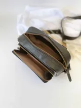 Bandolera negra de cuero con forro de tela, bolsillo interior y exterior.