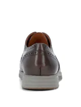 Zapato tipo Oxford con diseño brogue, confeccionado en cuero color marrón oscuro. Presenta cordones al tono y una suela de goma gris con diseño deportivo.