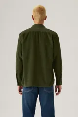 Camisa de pana color verde militar, con cuello clásico, cierre de botones frontales y dos bolsillos con solapa en el pecho.