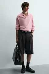 Bermuda negra de corte ancho (wide fit) confeccionada en tejido con mezcla de viscosa. Presenta pliegues en el delantero, bolsillos frontales y bolsillos de vivo en la parte trasera. Cierre frontal con cremallera y gancho metálico oculto.