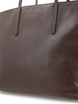 Cartera tipo shopper de gran tamaño, confeccionada artesanalmente en cuero graneado color chocolate. Cuenta con abertura principal con cierre, asas finas y bolsillos interiores para organización.
