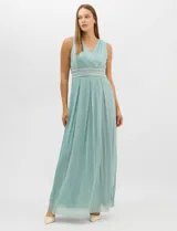Vestido largo de gasa con hilo metalizado lurex, color beige, con escote en V cruzado y drapeado, cintura alta con aplicaciones de strass y falda larga plisada con movimiento.