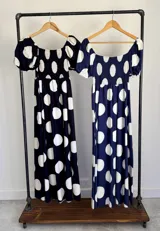Vestido largo de lunares con escote bote y hombros descubiertos, mangas cortas abullonadas, cuerpo con nido de abeja y falda amplia.