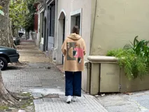 Campera tipo hoodie confeccionada en tejido de corderito color camel, con diseño de collage en la espalda que combina parches de diferentes texturas, colores y estampados geométricos. Presenta capucha y corte holgado.