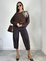 Sweater de punto oversized color verde, con escote en V y manga larga. Presenta un aplique bordado en forma de flor en el hombro izquierdo.