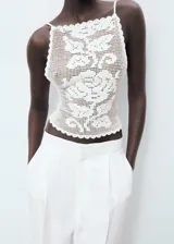Top halter blanco de crochet con diseño entallado, espalda abierta con tirantes finos cruzados y detalles de ondas en los bordes.