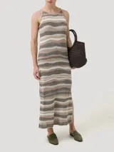Vestido midi de tejido de punto con diseño de rayas horizontales onduladas en tonos tierra. Presenta cuello redondo, tirantes finos y un corte recto con caída fluida.