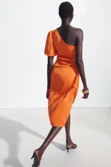 Vestido midi asimétrico de satén color naranja, con una sola manga corta abullonada, diseño drapeado en el lateral y falda cruzada.
