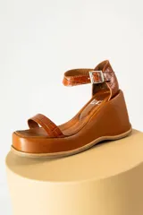 Sandalias negras de cuero sintético con plataforma y taco de cuña. Tienen dos tiras en el empeine y una tira con hebilla alrededor del tobillo.