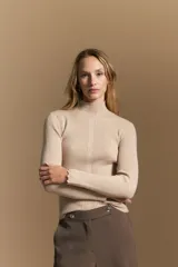 Polera de tejido acanalado con cuello alto, corte ajustado al cuerpo y mangas tres cuartos con terminaciones onduladas en los puños.