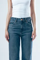 Jean de tiro alto con corte de pierna recta y diseño clásico de cinco bolsillos. Confeccionado en denim de tono azul medio con costuras en contraste.