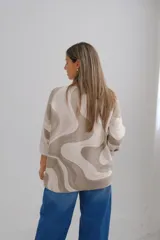 Sweater de punto amplio con escote en V y mangas largas, presenta un diseño estampado con ondas abstractas en tonos beige y verde oliva.