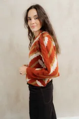 Sweater de punto jacquard con diseño de chevron en tonos celeste y marrón. Presenta cuello redondo, corte holgado y mangas largas con hombros abullonados.