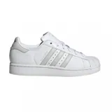 Championes adidas modelo Superstar, de diseño clásico con exterior de cuero blanco, puntera de goma reforzada y las icónicas tres tiras laterales en tono gris claro.