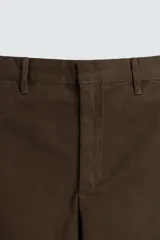 Pantalón de algodón color marrón oscuro, estilo balloon fit, con talle alto, cierre frontal y trabillas ajustables en los bajos. Presenta costuras verticales marcadas en el frente de cada pierna.