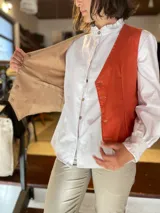 Chaleco reversible de lino, color naranja en el exterior y rayas finas en el interior, con cuello en V y cierre frontal de botones.