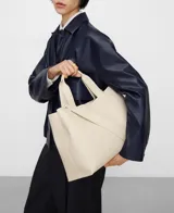 Bolso shopper horizontal negro de piel sintética, con dos compartimentos, cierre magnético y bolsillo interior con cremallera. Cuenta con asa de mano y correa larga regulable y extraíble, además del logo grabado en el frente.