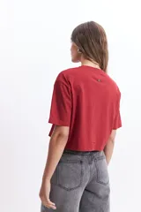 Remera corta (cropped) de algodón color verde lima, con cuello redondo y manga corta. Presenta un pequeño estampado en el pecho con un corazón naranja y texto manuscrito.