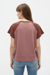 Remera de manga corta con diseño color block en tonos rosado y marrón, con escote en V y cartera con botones frontales.