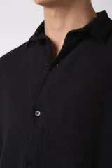 Camisa de manga corta confeccionada en lino, con cuello clásico y cierre frontal de botones. Presenta un corte relajado y una textura natural característica del tejido.