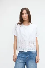 Blusa corta de broderie blanca, de manga corta, con cuello redondo y cierre frontal de botones.