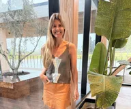 Musculosa de tejido de punto gris, con tirantes finos, escote en V y un llamativo aplique frontal de cuero plateado en forma de flecha.