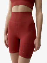 Short deportivo de tejido seamless en color rojo, tiro alto y diseño ajustado con detalles de perforaciones laterales y pequeño logo reflectante.