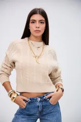 Sweater de punto con diseño de trenzas, color beige, de corte cropped y cuello redondo.