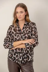 Camisa de manga larga con estampado de leopardo, cuello clásico y cierre frontal de botones. Presenta un corte holgado y puños abotonados.