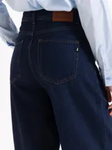 Pantalón de jean azul oscuro de tiro alto y silueta slouchy, con costuras a la vista y cierre frontal con botón metálico.
