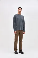 Remera manga larga de algodón lavado con textura suave, color gris oscuro, con estampado pequeño en el pecho y estampado en la manga.