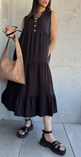 Vestido midi negro con escote en V, sin mangas, corte holgado y tres botones en la parte superior.